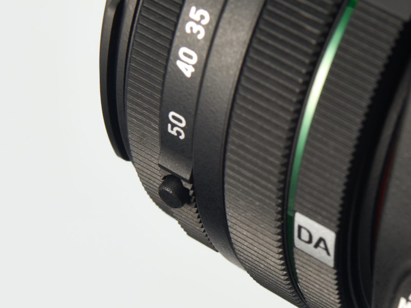 レンズを伸長するにはロックボタンを押しながらズームリングを回す