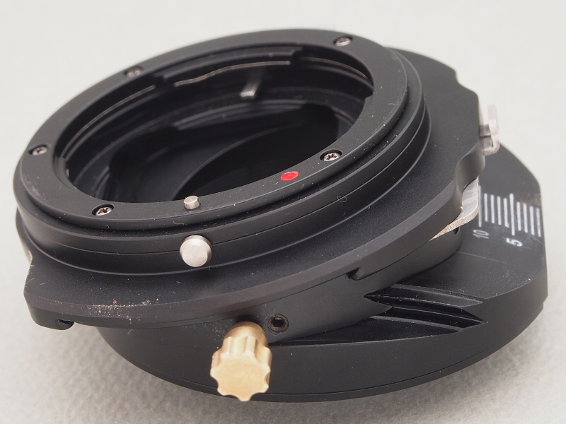 前回と同様、KIPON製の<a href="http://item.rakuten.co.jp/auc-stkb/ts-ng-fx-kipon-db/" class="n" target="_blank">シフト/ティルト機能付きマウントアダプター</a>（焦点工房扱い）を使用する。レンズ側がニコンFマウント、ボディ側がXマウントなのも同様だ。しかし今回はアダプターの「ティルト機能」だけを使用する。このアダプターには円弧状の溝が掘ってあり、それに沿ってレンズの光軸を最大12度傾けることができる。ティルトの動作はなめらかで、ガタ付きなくしっかり固定できる。