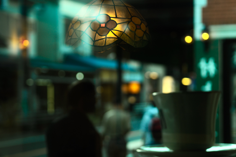 喫茶店の窓に映る景色。コーヒーカップのオブジェ、通りすがりの男性の影、店内のうっすらとした明かりとランプシェード。すべてをガラスに写すことで異空間を作った。<br class=""><span class="fnt-85">オリンパス PEN-F / M.ZUIKO DIGITAL 45mm F1.8 / 45mm（90mm相当） / 絞り優先AE（F1.8、1/640秒、-0.3EV） / ISO 200</span>