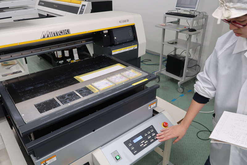 プラスチック樹脂にて射出成型されたランナーを、インクジェットプリンターにて彩色している風景（ちなみに1/12のお皿シリーズもイベントでテスト販売されているが、全国的な発売時期はまだ未定。ただし価格はやはり税別1,500円の予定だ）。エムアイシーが導入したインクジェットプリンターは相当に繊細な印刷が可能で、プロモデラーでも塗装再現が不可能なようなものが簡単に印刷できてしまう