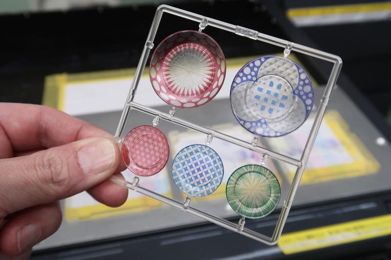 プラスチック樹脂にて射出成型されたランナーを、インクジェットプリンターにて彩色している風景（ちなみに1/12のお皿シリーズもイベントでテスト販売されているが、全国的な発売時期はまだ未定。ただし価格はやはり税別1,500円の予定だ）。エムアイシーが導入したインクジェットプリンターは相当に繊細な印刷が可能で、プロモデラーでも塗装再現が不可能なようなものが簡単に印刷できてしまう