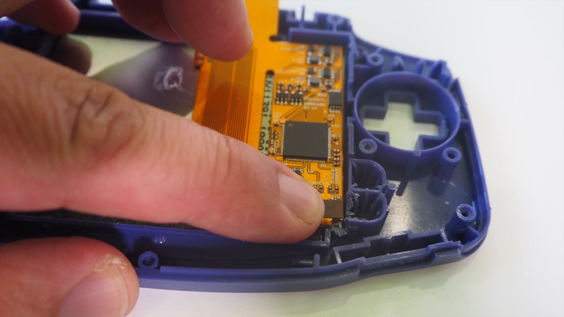 液晶の右下から出ているフレキを折り曲げて、コネクタを液晶制御用基板のコネクタに押し込んで接続する（人差し指で押している部分）