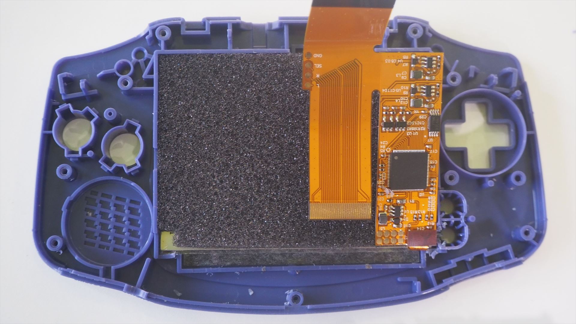 IPS液晶交換用キットに付属していたスポンジをこのように液晶と液晶制御用基板の間にいれる。初期型と後期型で基板に接続するフレキのピン数が異なる。初期型は40ピンなので、この写真で上に見えているフレキをそのまま基板に接続すればよいが、今回改造したゲームボーイアドバンスは後期型なので、下に見えているフレキの32ピン側を折り返して接続する必要がある