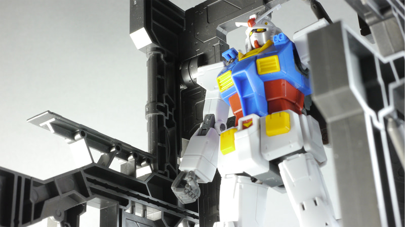 「ビルダーズパーツ 1/144 システムベース 001 (ガンメタ)」を使用してガンダム開発中のイメージで撮影してみた。ちなみに、ガンダムの型式番号はアニメ版ジ・オリジンはRX-78-02、漫画原作ではRX78-02、ファーストでRX-78もしくはRX-78-2となる。この細かい違いがファンの心理をくすぐるのだ