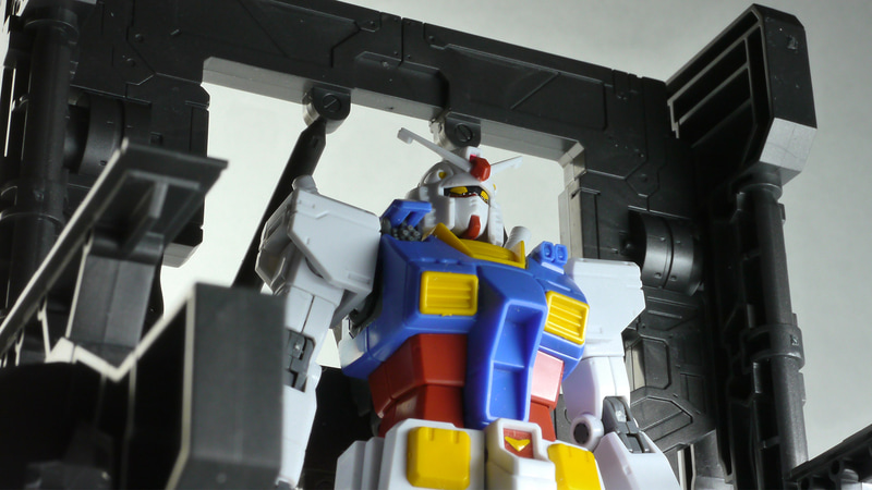 「ビルダーズパーツ 1/144 システムベース 001 (ガンメタ)」を使用してガンダム開発中のイメージで撮影してみた。ちなみに、ガンダムの型式番号はアニメ版ジ・オリジンはRX-78-02、漫画原作ではRX78-02、ファーストでRX-78もしくはRX-78-2となる。この細かい違いがファンの心理をくすぐるのだ