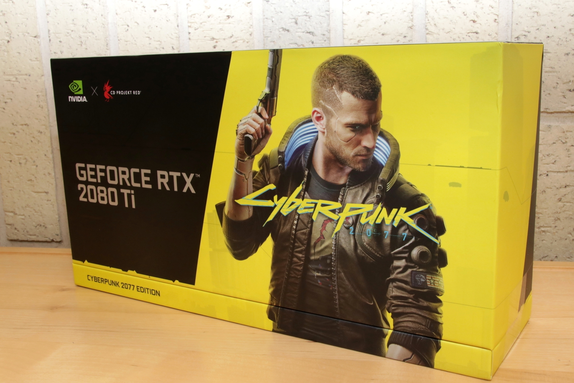 表面にはロゴと主人公「V（男性）」の姿が描かれ、「GeForce RTX 2080 Ti」と「Cyberpunk 2077」のダブルネームが側面と天面に記されています。カッコええ……。プレゼント品は未開封となりますので、中身は上記動画にてご確認ください