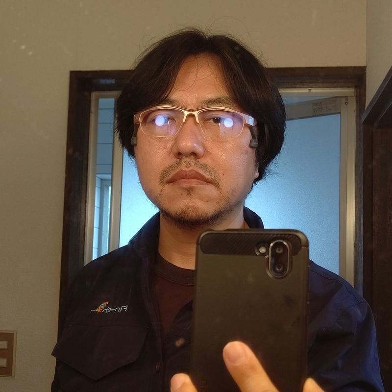 鏡の前でフィッティング中の筆者。かけ心地が一般的な眼鏡とかなり違うので、フィッティングにはかなり試行錯誤が必要だ。レンズが垂直、あるいはごく僅かに下向きになるように調整するのがいいだろう