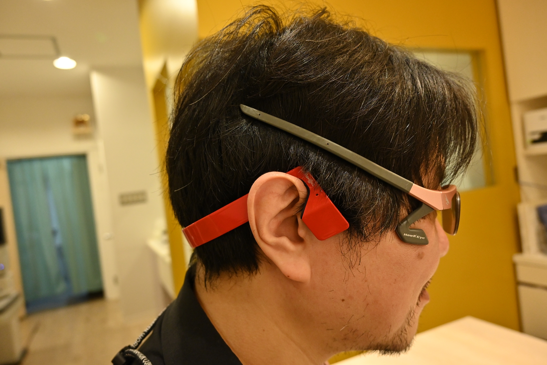 あえて髪の上にツルを出すと、こんな角度になる。イヤーパッドの大きな「GSP 600」でもツルが当たらないのがわかるだろうか。また、耳にかける形で装着するAftershokzの骨伝導ワイヤレスヘッドフォンもこのように「HawkEye」とは干渉しない（撮影：志田彩香）