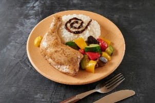 メインは、厳選した若鶏の骨付きレッグのローストチキン。彩りのグリル野菜が添えられている。サンジのトレードマークであるサンジのぐるぐるまゆげをイメージし、岩海苔でぐるぐるを表現！