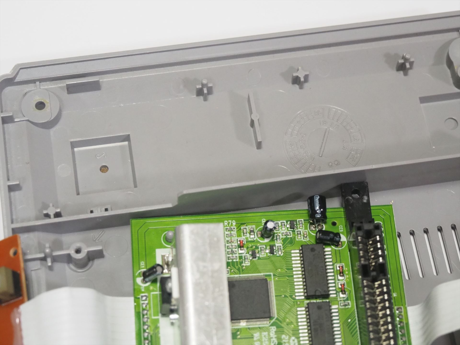 基板の穴と、裏蓋の基板固定用の出っぱりを合わせてみたところ、カセットのスロットの端が壁部分と干渉するので、その部分に穴を空けることにした