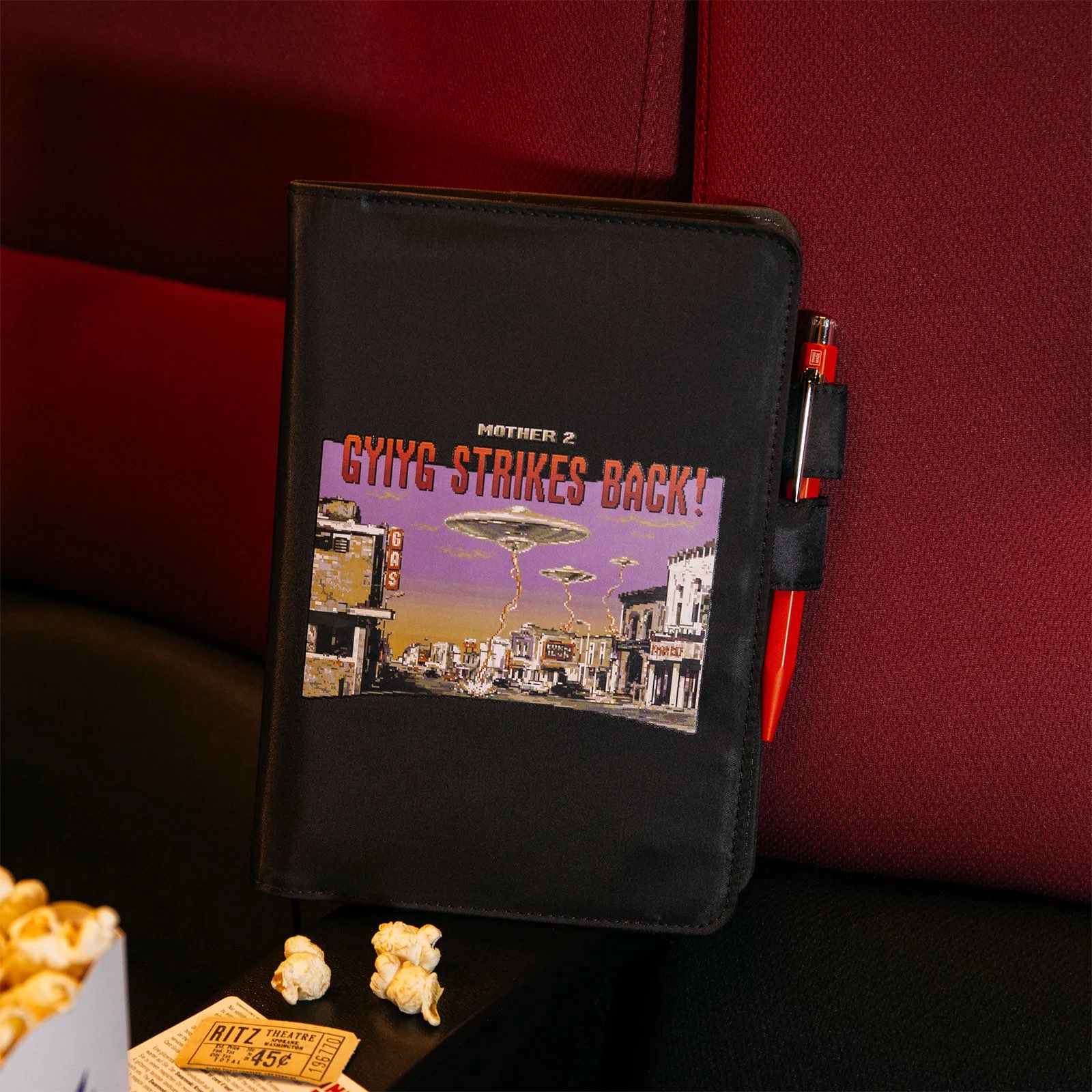 ほぼ日手帳カズン（A5）サイズの「STRIKES BACK!」は真っ黒なポリエステルの生地に、「MOTHER2」のオープニングシーンがプリントされたカバー。カバーの裏側には、UFOから発せられるビームによって空一面が光っているようすがプリントされている