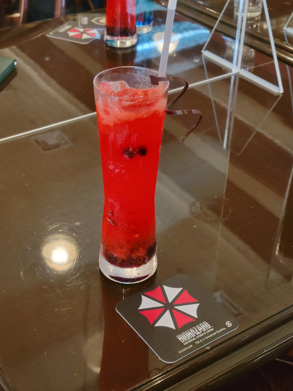 独特のマーブルカラーのドリンクが「リッカー ～t-ウィルスの突然変異～」で、鮮やかな赤色のドリンクが「ハウンドウルフ ～クリス・レッドフィールドが率いる精鋭部隊～」だ。クリスイメージのドリンクはともかくクリーチャーをイメージしたドリンクと言うのは中々に攻めた内容だが味はしっかりと甘味を感じる内容となっている。どちらも注文するとそれぞれのシンボルが描かれたコースターをゲットできる！