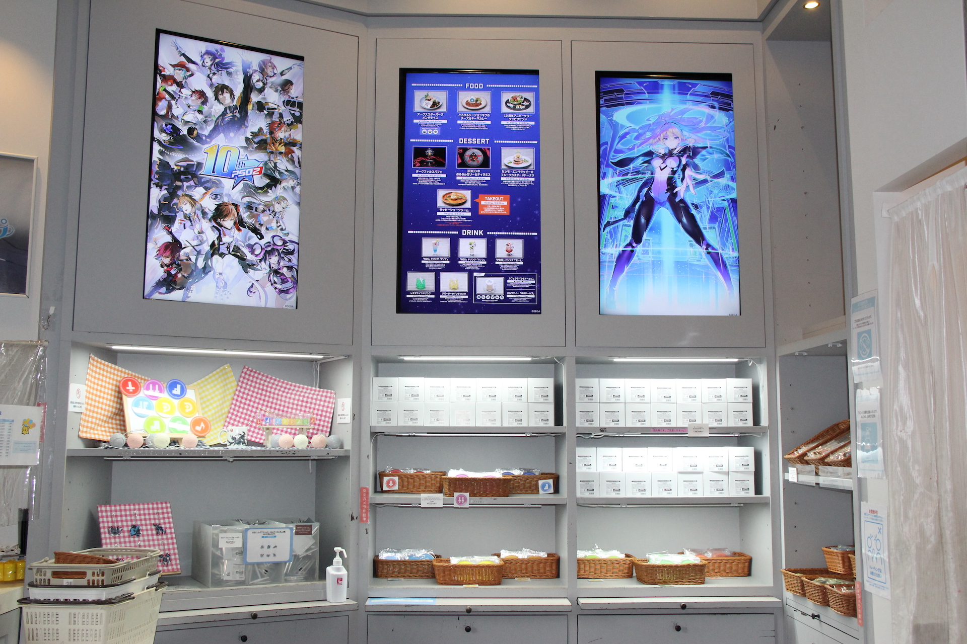 店内左手側では、各種グッズを販売中。その上部にある中央のモニタには、店内で注文できる飲食のメニューが映っている