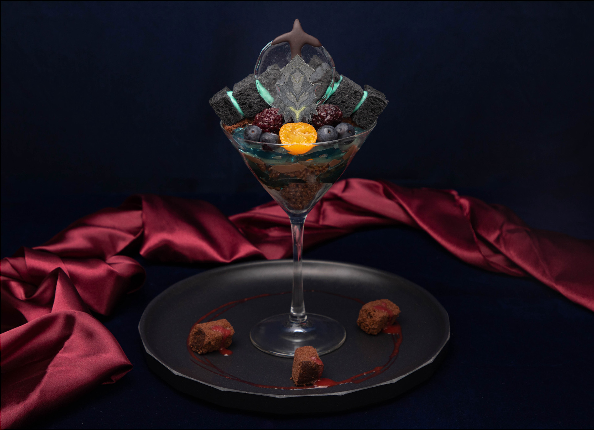 ダークファルスパフェ(税込1,540円)　「NGS」に登場するダークファルスの第1形態をイメージした、黒に青が映えるチョコレートパフェ。写真ではそう見えないが、実は思った以上に大きい。何も知らずに頼むと、倒せ（完食でき）なくて後悔するかもしれない!?