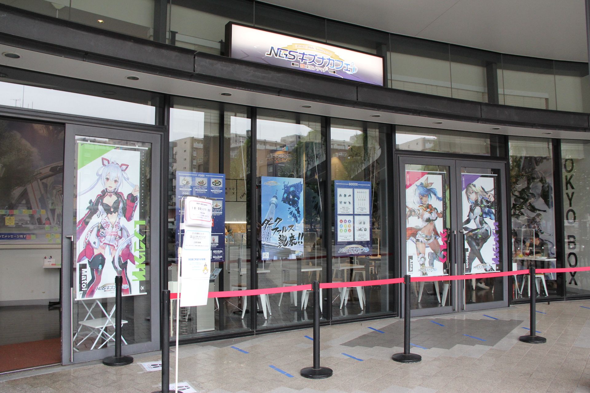 入り口の看板には、「NGSキズナカフェ」と大きく描かれているのが目立つ。窓には商品案内ポスターが張ってあるほか、ヒロインタペストリーも飾られている