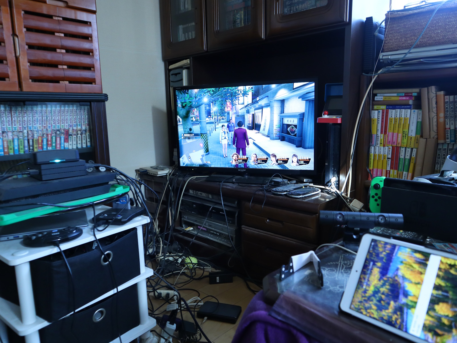 筆者弟のゲーム環境。画像左側にあるPS4に無線ユニットを接続し、右側のタブレットからは動画を再生した。ゲームは「龍が如く7」だが、街の雑踏からキャラクターたちの声や息遣いがリアルに伝わると同時に、パーティーチャットの音声も鮮明に聞こえてきた