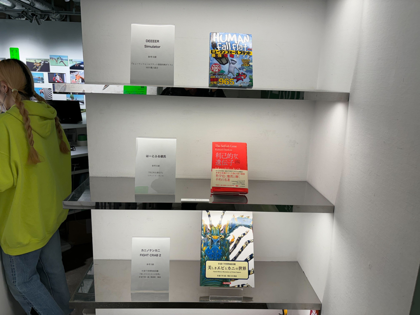 ゲーム制作の際に参考にされた書籍が展示。「美しきエビとカニの世界 杉浦千里博物画図鑑（成山堂書店）」といった図鑑や、科学書「利己的な遺伝子（紀伊國屋書店）」などが置かれている