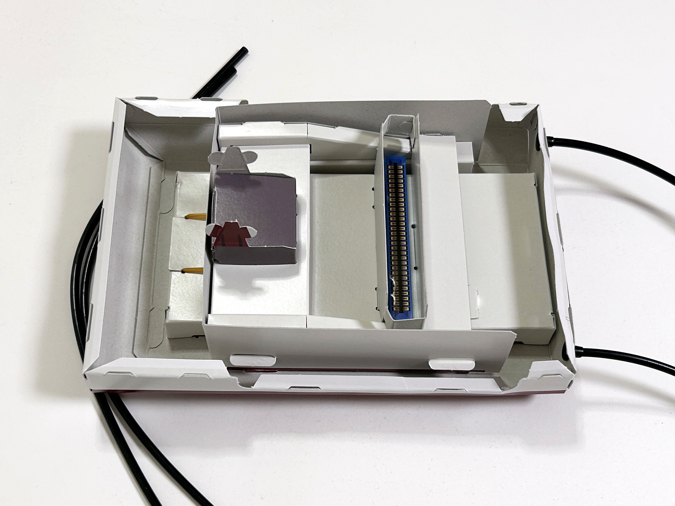 上面と下面を組み合わせるため、下面部分の折り目を曲げる。合わせて、黒色コードをポリキャップに差し込み、下面の背面部分に繋いでおく。ここに、コントローラーが繋がる仕組みだ