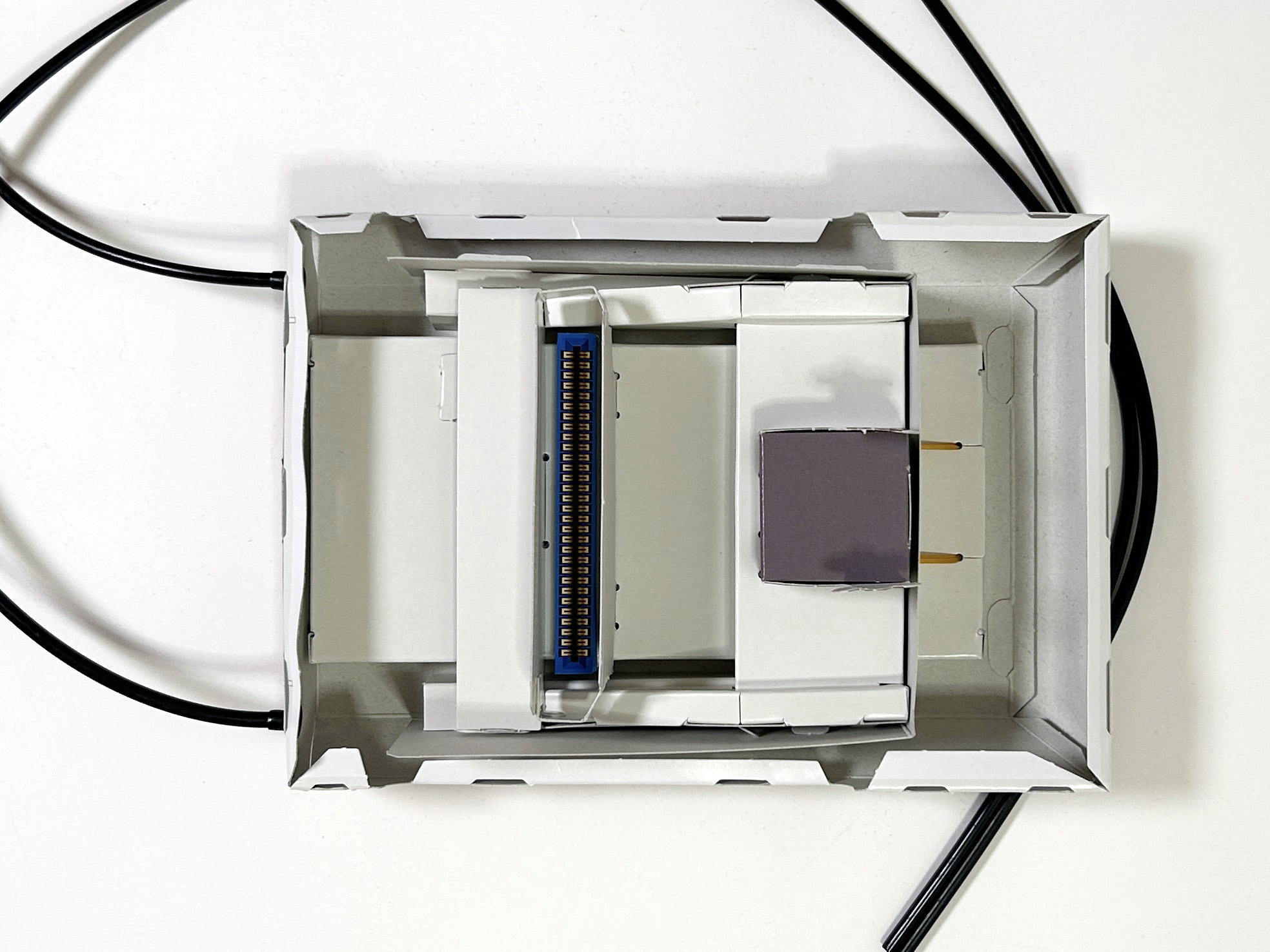 上面と下面を組み合わせるため、下面部分の折り目を曲げる。合わせて、黒色コードをポリキャップに差し込み、下面の背面部分に繋いでおく。ここに、コントローラーが繋がる仕組みだ