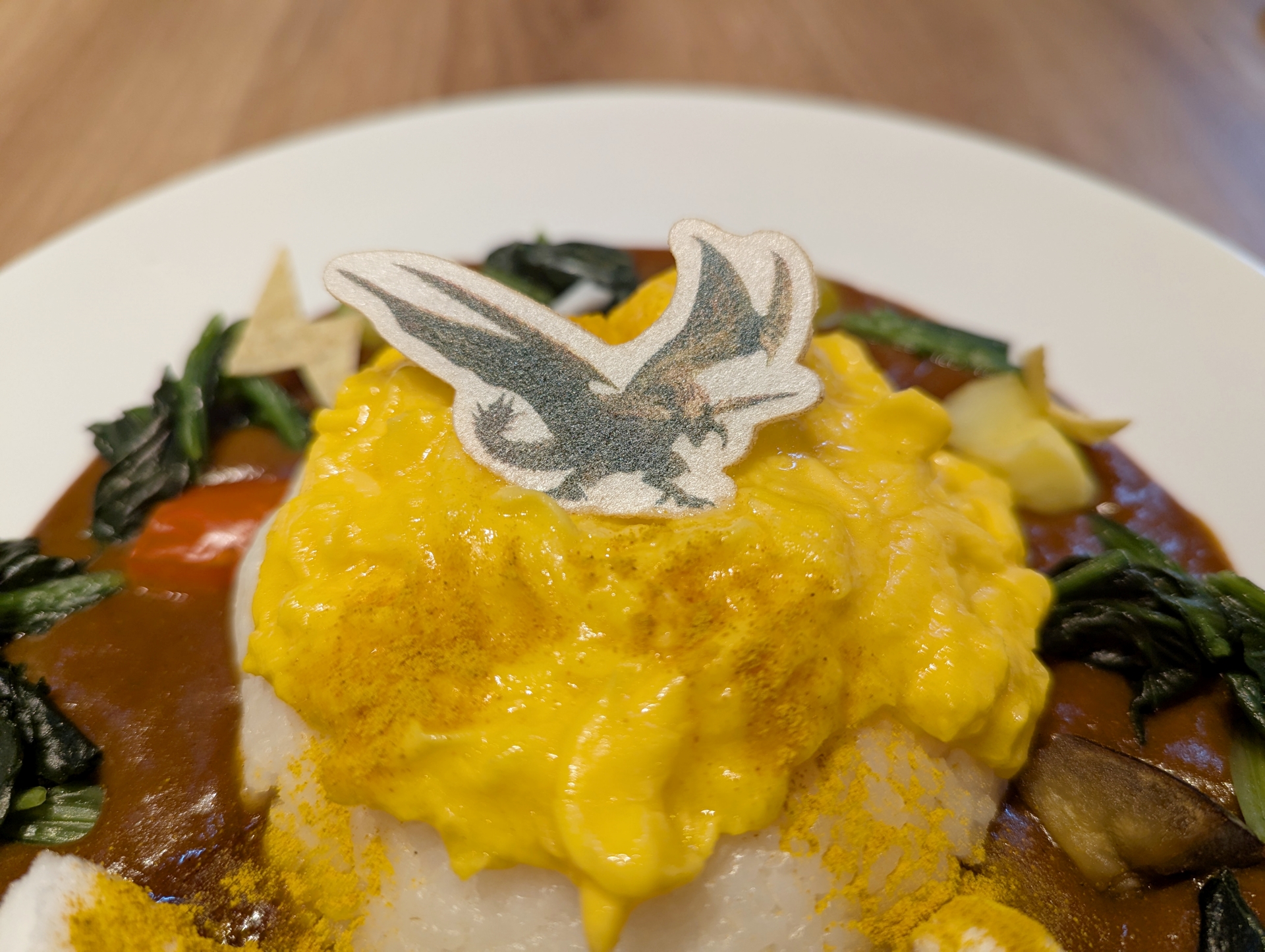 中央のオムライスの頂上にはワイバーンのようなビジュアルのモンスター「レ・ダウ」のイラストの最中がドンと身構える