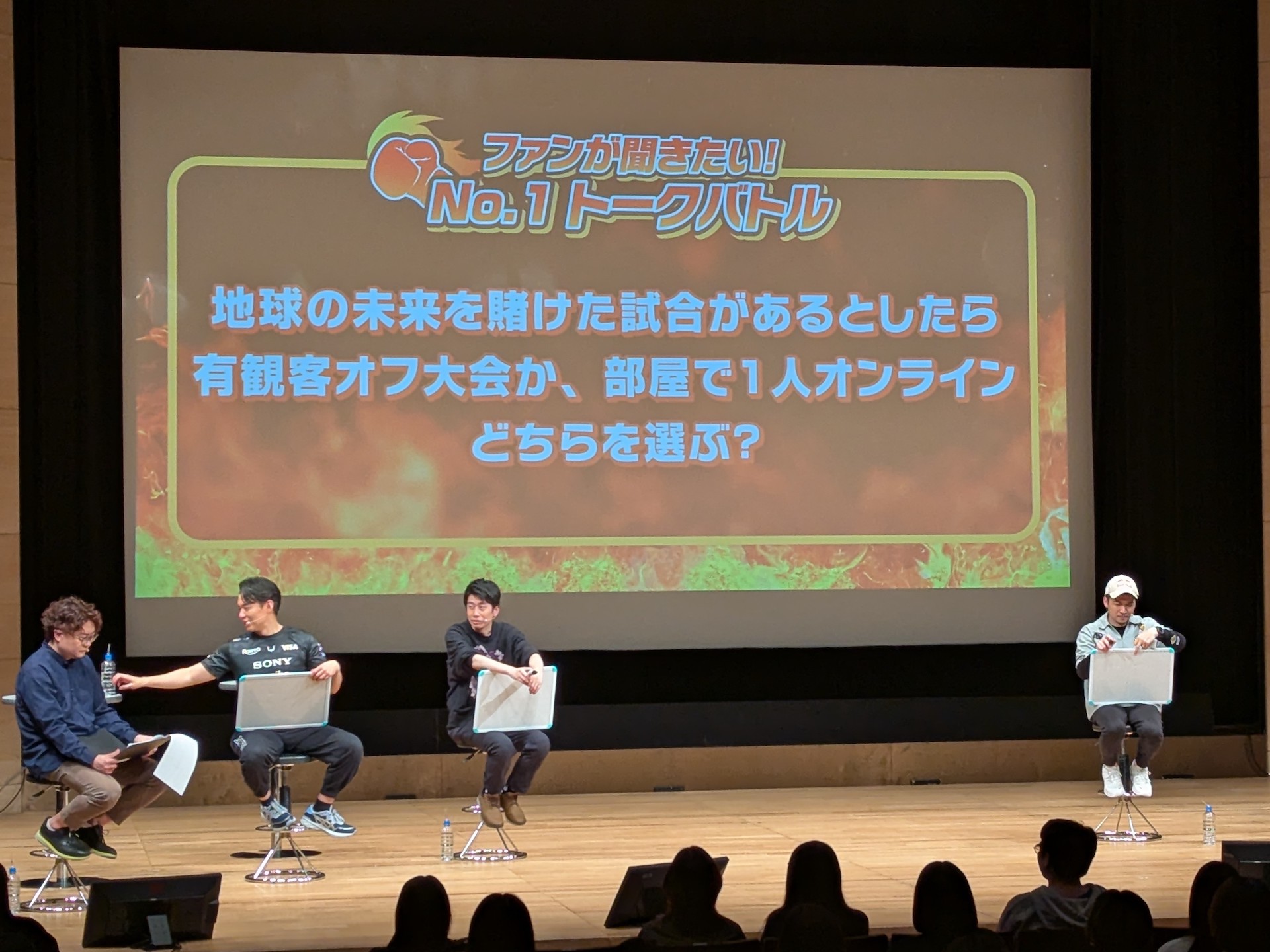 「地球の未来を賭けた試合があるとしたら、有観客のオフライン大会か、部屋で1人でプレイできるオンライン大会のどちらを選ぶ？」の質問では、現在も選手として活動するときど選手、ガチくん選手、マゴ選手の3人がオフラインを選び、ストリーマーとして活動するハイタニ氏とこく兄氏がオンラインを選択したのが印象的。ガチくん選手は先日の両国国技館でのエピソードも交え、観客の声が力に繋がる点をアピールしていた