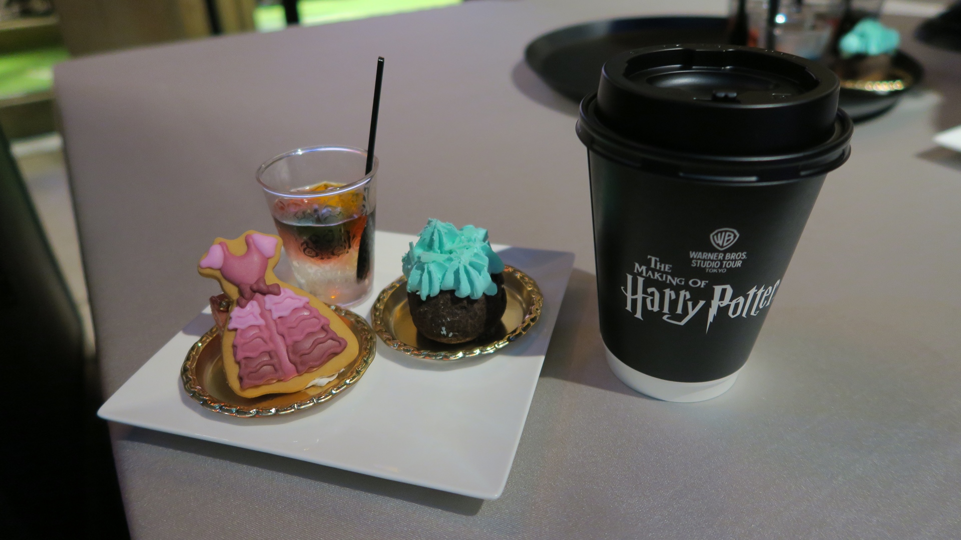 【デザート】ハーマイオニーのドレスクッキー、大鍋シュー、ステンドグラスベリーヌ。デザートを館内ツアー中に立食形式で楽しめるようになっている。ハーマイオニーのドレスをイメージしたアイシングクッキー「ハーマイオニーのドレスクッキー」、チョコミント味のシュークリーム「大鍋シュー」、そしてカラフルなジュレが楽しめる「ステンドグラスベリーヌ」をコーヒーまたは紅茶と共にいただける