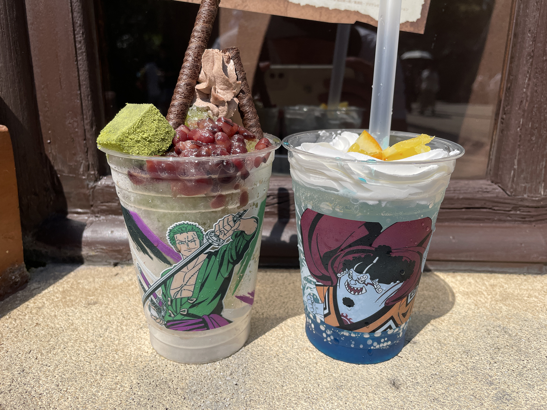 剣士ゾロの抹茶氷 ～小豆＆わらび餅～（左）、ジンベエの渦潮ソーダ ～ライム＆オレンジ～（右）