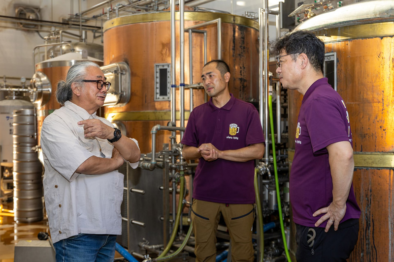 タンクを前に、世嬉の一酒造の2人にビール造りについて質問をする植松氏