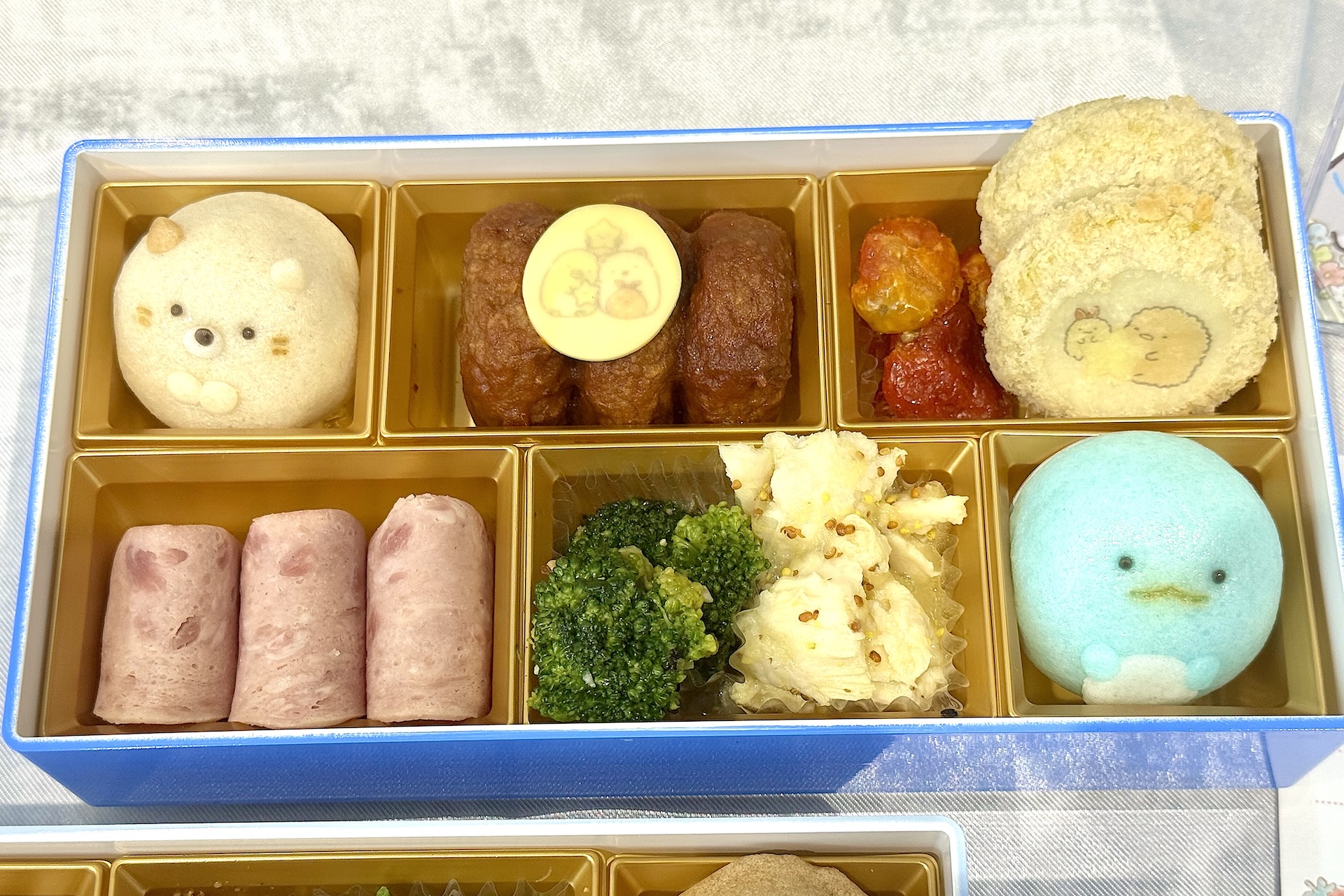 三の重：お子さま重。小さな子どもが喜びそうなミニサイズのハンバーグなどが入っている。各段に入っているすみっコたちを再現した5種のじょうよ饅頭がめちゃかわ