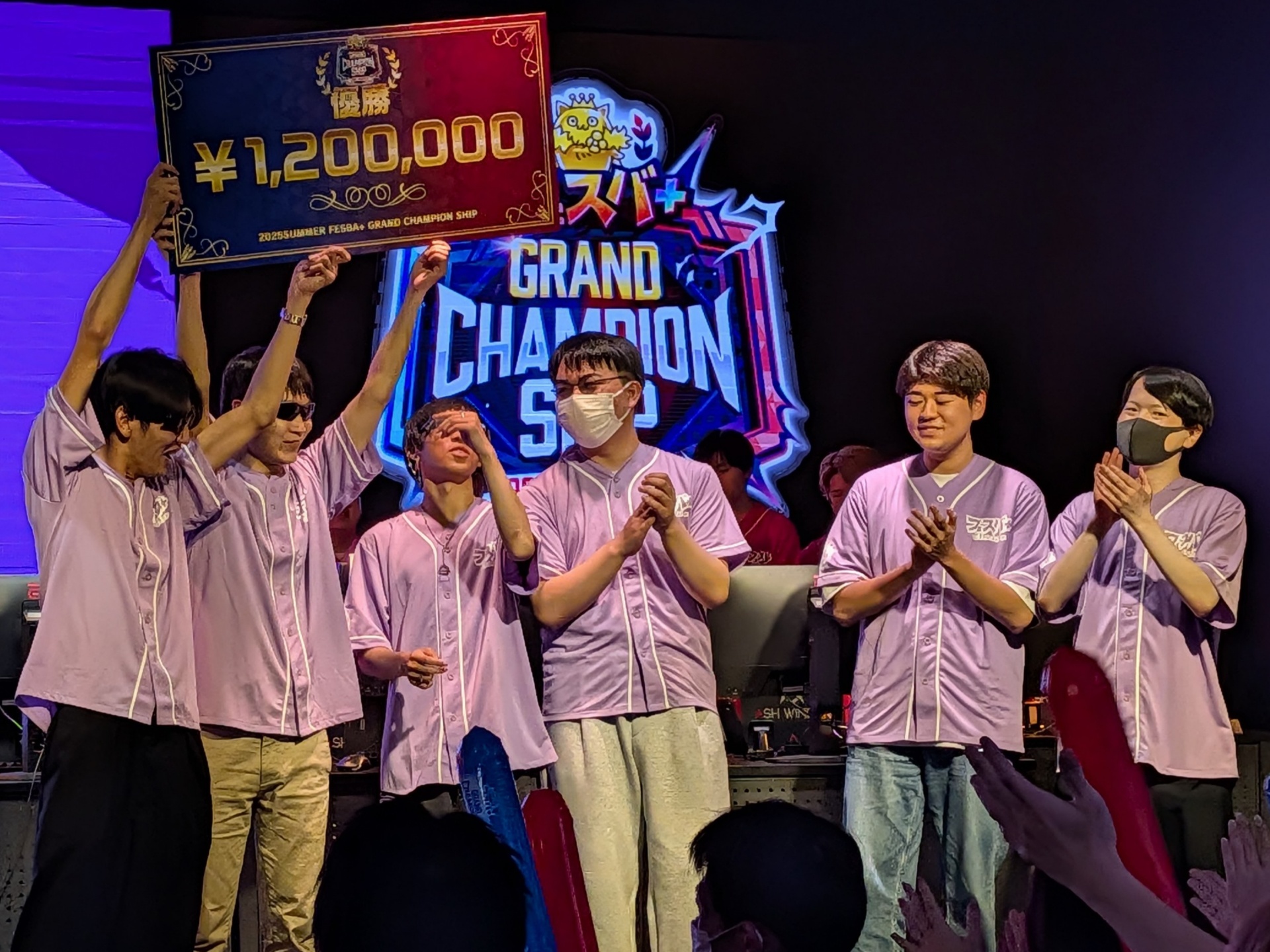 優勝賞金120万円のプレートを天に掲げるリーダーのキャプテンとメンバーたち