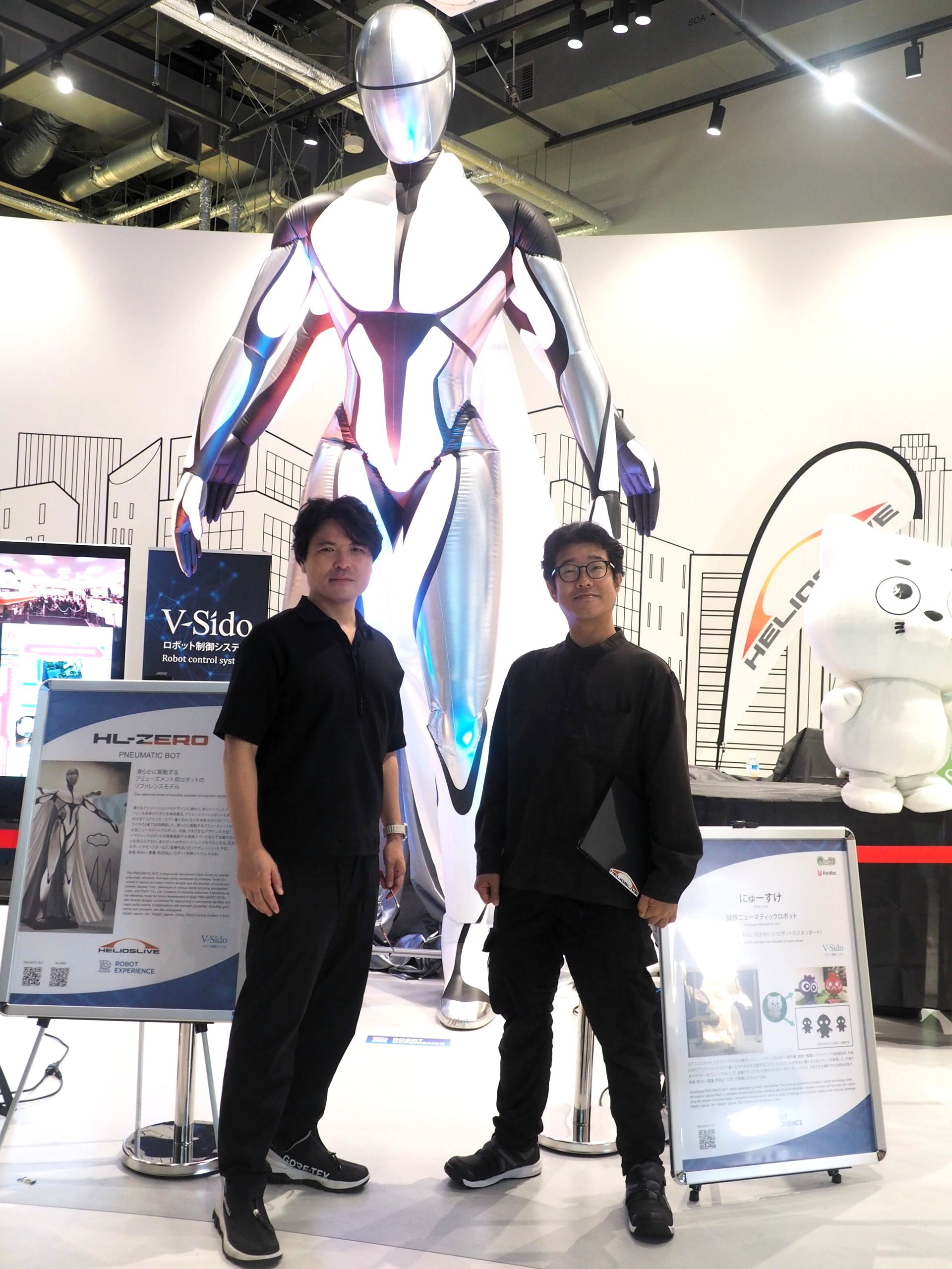 左がメカデザイナーの天神英貴氏、右がV-Sidoを開発したアスラテックの吉崎航氏。2人はHL-ZEROよりもかなり前に立っており、後ろのHL-ZEROの大きさがよくわかる