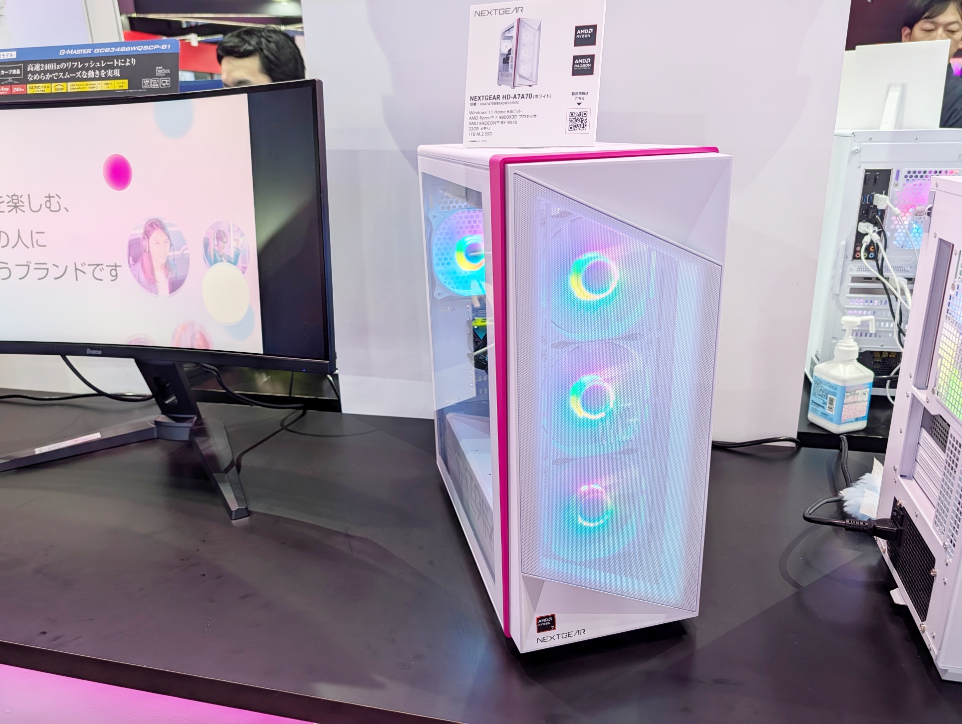 「<a href="https://www.mouse-jp.co.jp/store/g/gngear-hda7a70w8afdw102dec/?utm_source=gawt&utm_medium=content-text&utm_campaign=2509_tgs_gw_03&utm_content=pr">NEXTGEAR HD-A7A70（ホワイト）</a>」も並べられて設置されている