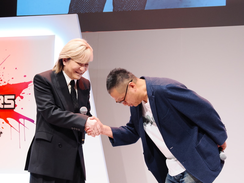 岡本吉起氏(右)と小室哲哉(左)が握手を深く交わす場面も