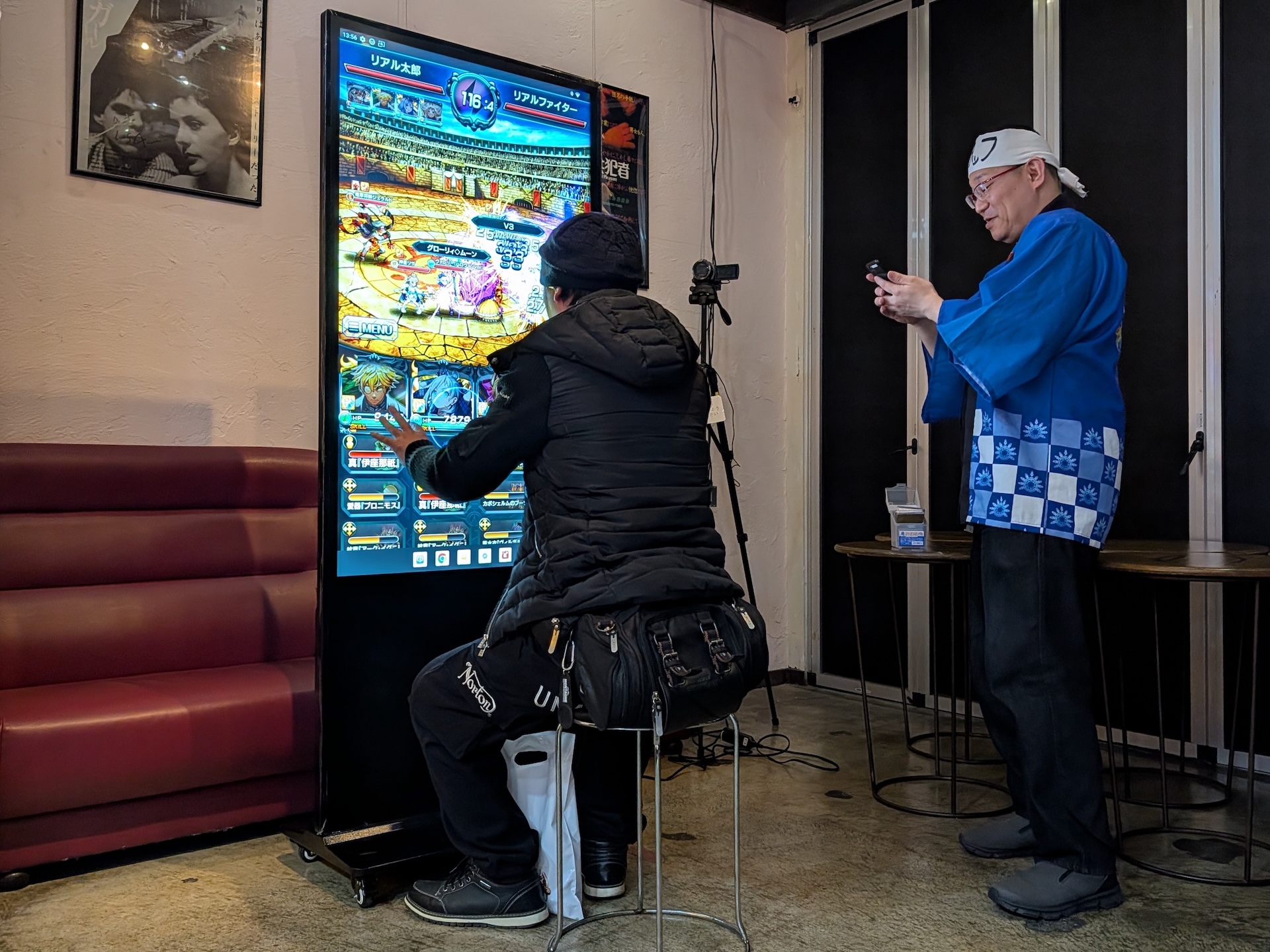 会場に設置された大型ディスプレイを使って新永氏とリアルバトル！ 新永氏は手持ちのスマートフォンを利用し、来場者たちは大型ディスプレイで対戦する