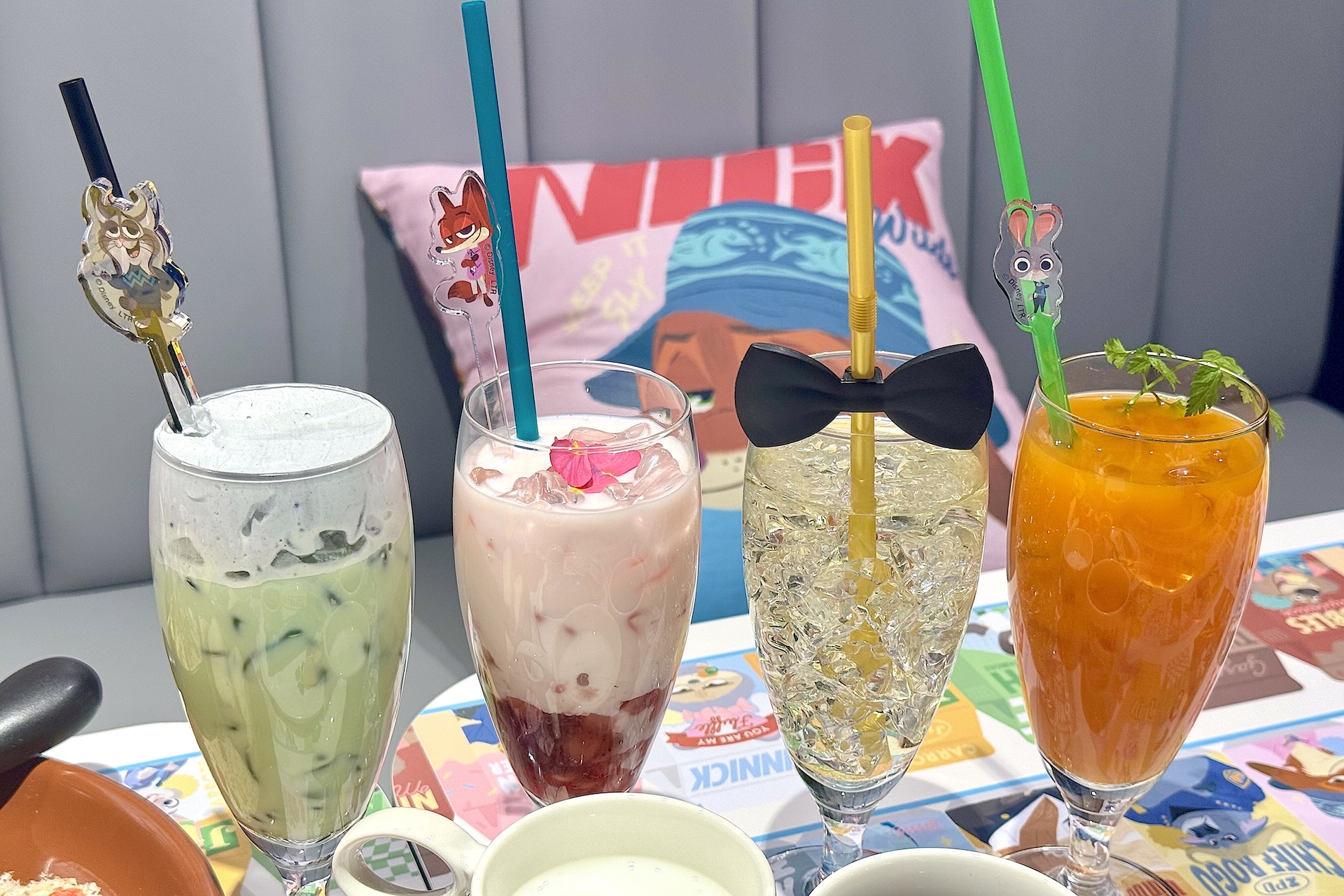 左から＜パウバート＞マッチャラテ、＜ニック＞ストロベリーラテ、＜ズーテニアル・ガラ＞スパークリングドリンク、＜ジュディ＞ニンジンソーダ 各990円 特典コースター付き ※アクリルマドラーはお持ち帰りできません