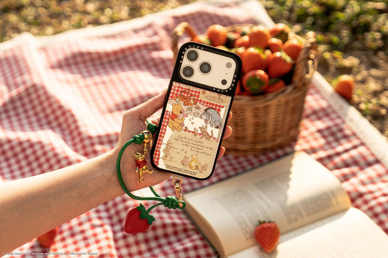 ディズニー「くまのプーさん」ベリー スマホストラップ：イチゴの蔓をイメージしたグリーンのレザーコードに、バルーンで浮かぶプーさんのゴールドチャームと、レザー製のイチゴがあしらわれている