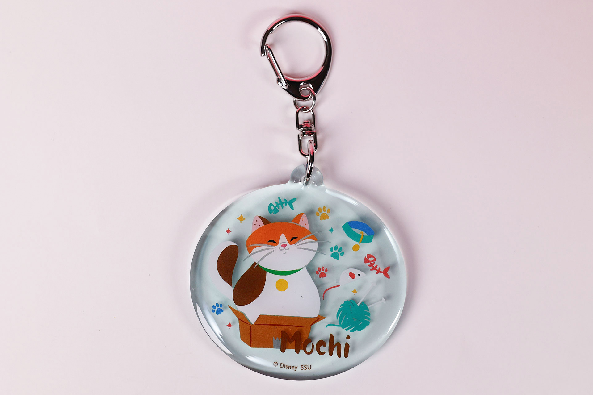 モチのアクリルキーホルダー。円形デザインにかわいい絵が描かれている