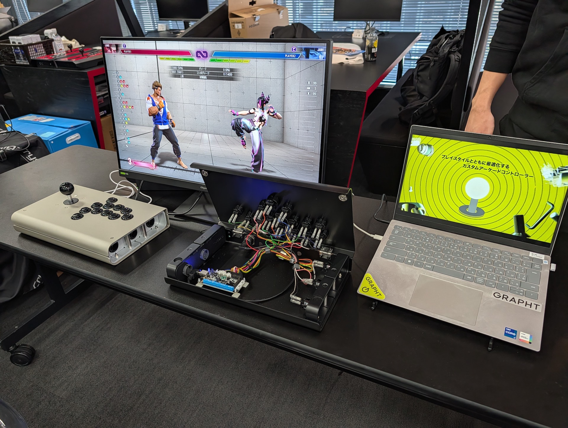 GRAPHTのブースでは、発売中のレバーレスコントローラ「iO（イオ）」を展示。店頭販売バージョンは直販バージョンと比べて、組み立て時のコストが乗るためやや高くなっているが、背面部に貼られた滑り止めの分は価格に上乗せしていないらしい