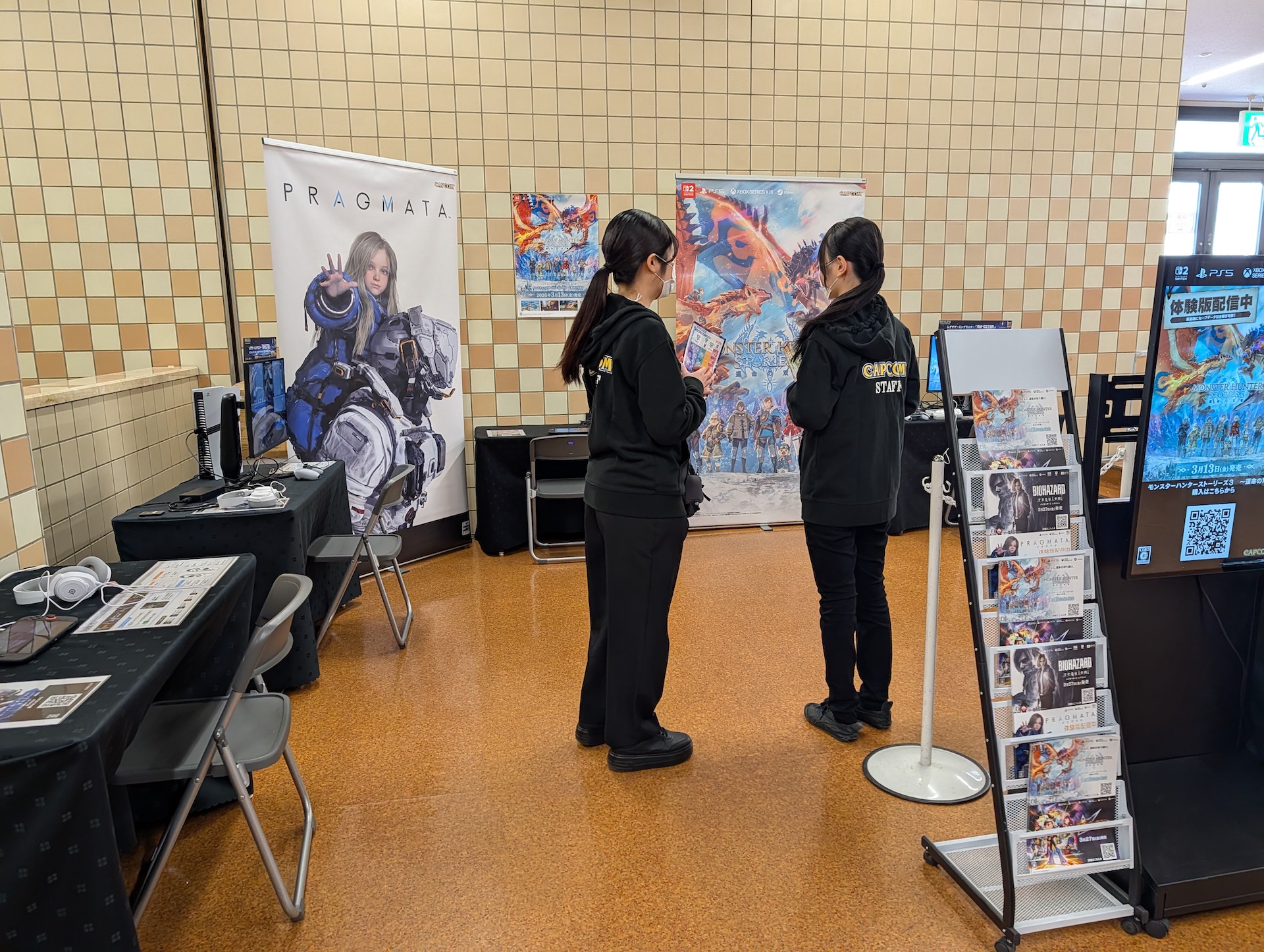 「プラグマタ」と「モンスターハンターストーリーズ3 ～運命の双竜～」の試遊台。開場前のため、スタッフが準備している途中の様子だが、比較的小さなブースとなっている印象だ