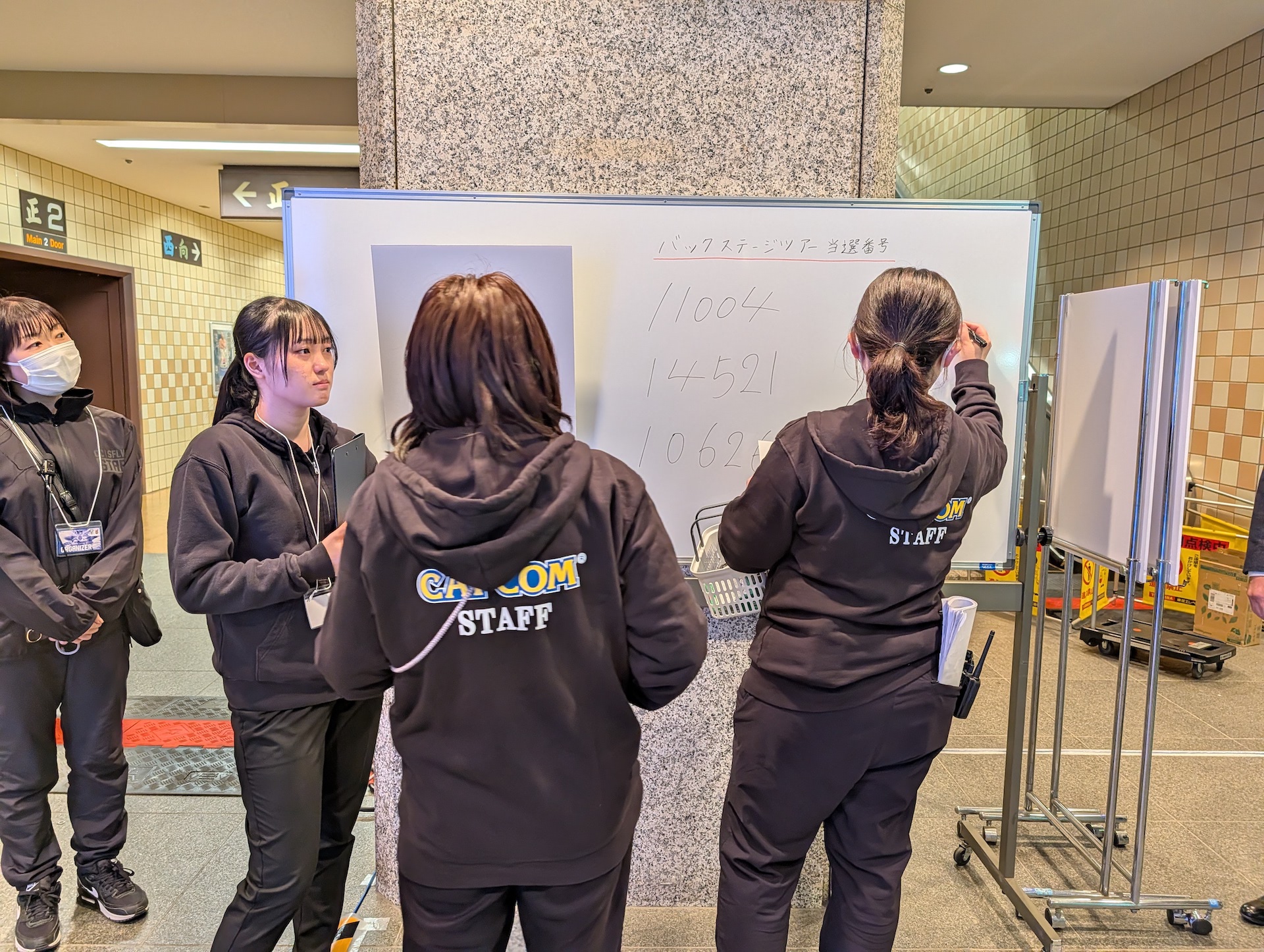 「バックステージツアー」の当選者は入口付近のディスプレイそばにおかれたホワイトボードのもとに集まる。ここで番号が発表され、当選番号の確認なども行なわれる