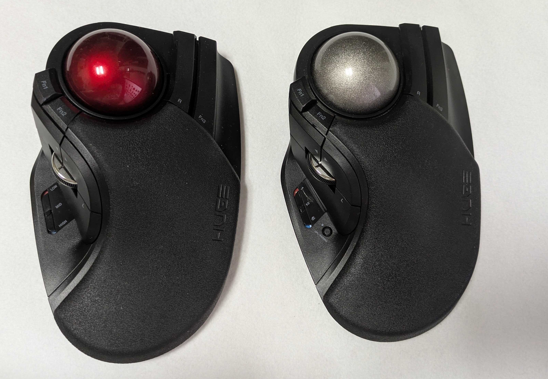 姉妹機「HUGE」（左）と比べると、外見上の違いはボールの色と本体左側のインターフェース部分くらい。「HUGE PLUS」は有線/無線両対応、そしてベアリングユニットがデフォルトで搭載されているなど内部機構の違いが大きい。上位機種にあたる「HUGE PLUS」は確かに触り比べると素晴らしいものだが、では「HUGE」が時代遅れかと言うと全くそんなことはない。手に取りやすい価格でこのやたらデカくて操作感のいいデバイスが手に入るというのは非常に有り難いところだ