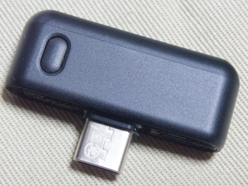 Arctis Nova 7 Gen 2のUSB-Cドングル。ドングルと本体はあらかじめペアリング設定がされた状態で出荷されている。改めてペアリングを行う場合は、ドングルを再生機器のUSBポートと接続したうえで、ドングルのペアリングボタンを長押し、さらにヘッドセット側の電源を一度切ってから電源ボタンを長押ししてこちらもペアリングモードにすることでかんたんにペアリングが実行できる