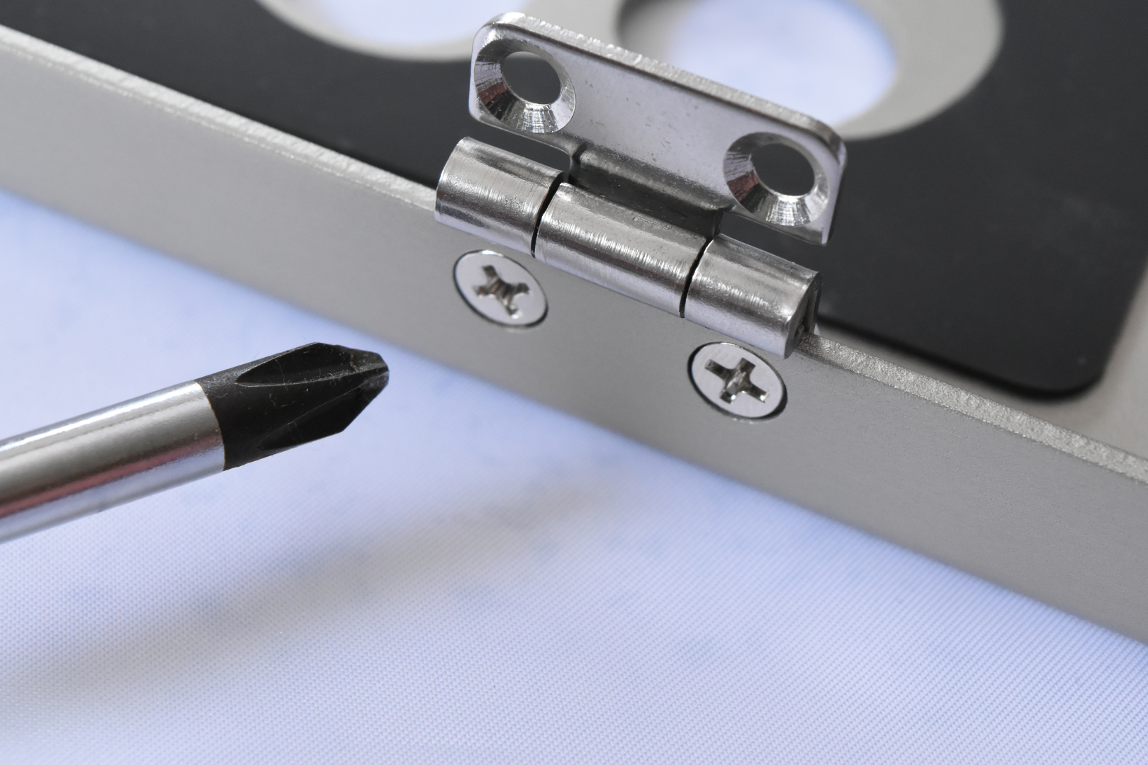 蝶番の向きはこの写真と同じ向きで取り付けよう。ナットで軽く固定したら、最後はナットをペンチで押さえながらドライバーを使って固く締めよう