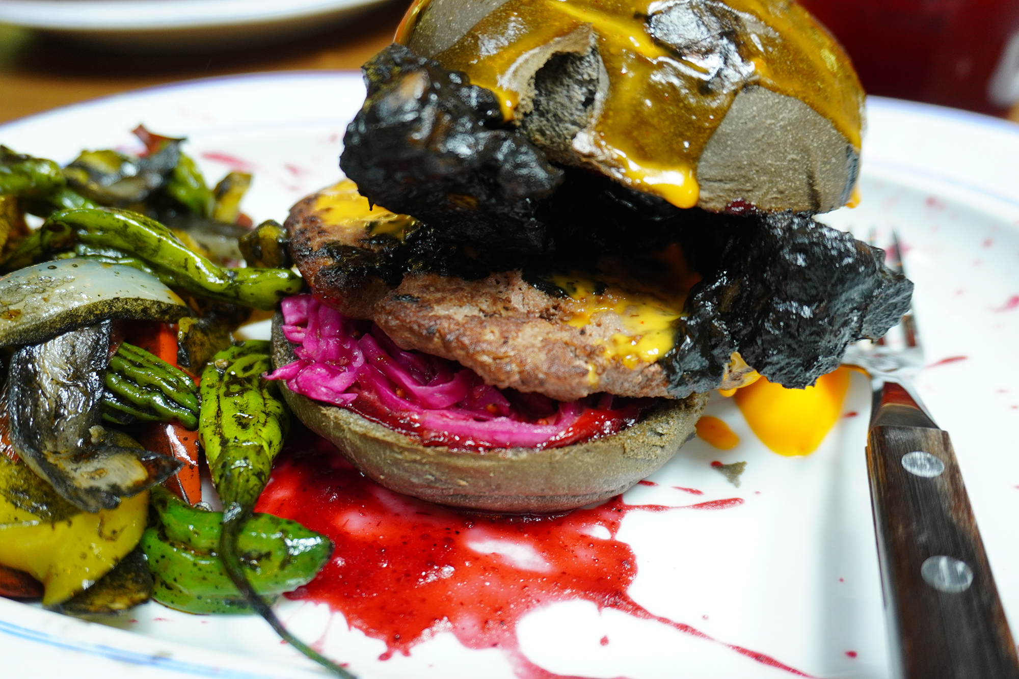 黒こげ骨付き肉とバンズの下にはこれまた毒々しげな紫キャベツ。実際にはどれも普通に美味しい