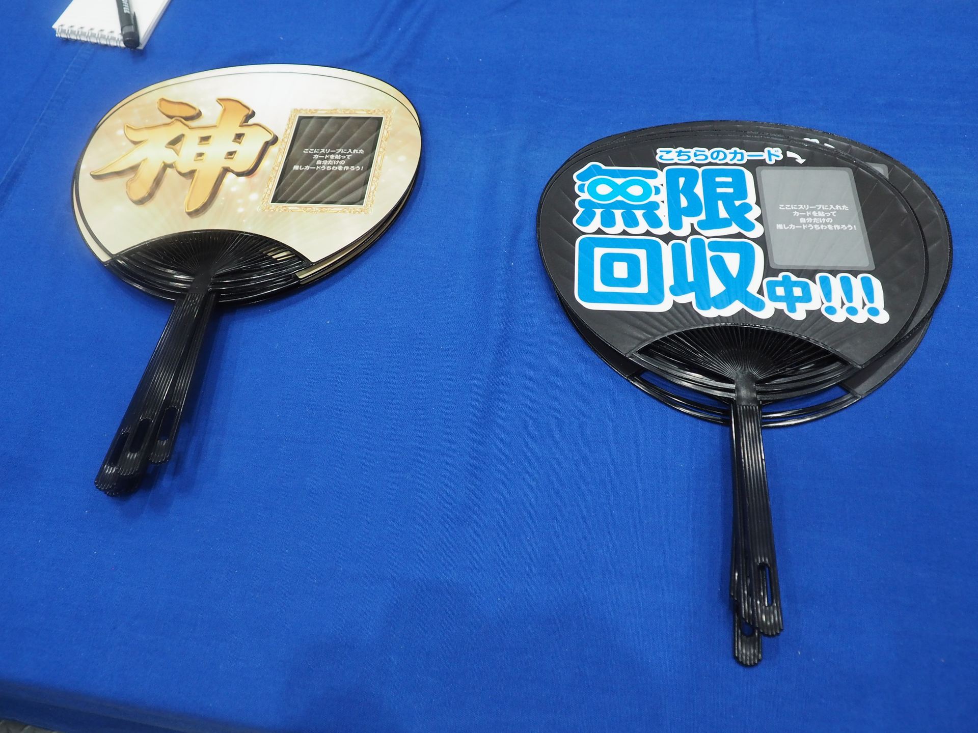 左は神カードをアピールするうちわ、右は無限回収中の推しカードをアピールするうちわ