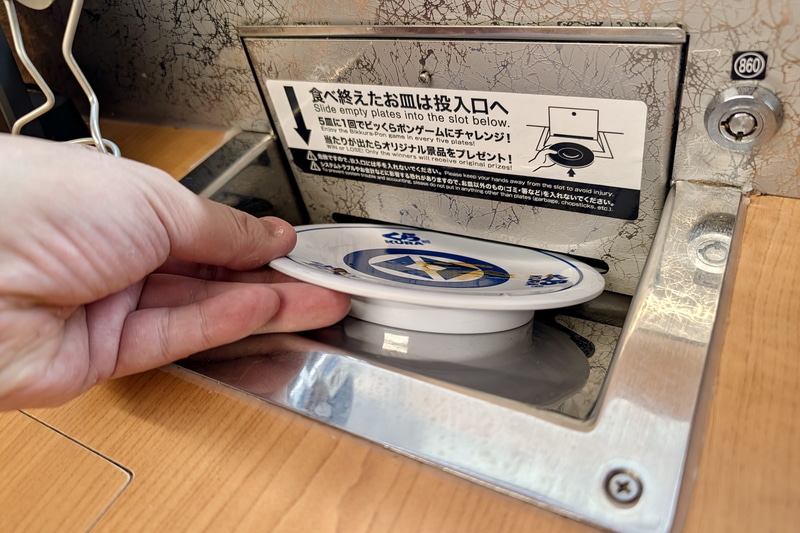 「ビッくらポン!」は、テーブルに備えるお皿の回収口にくら寿司の寿司用皿を5枚投入することで実施される
