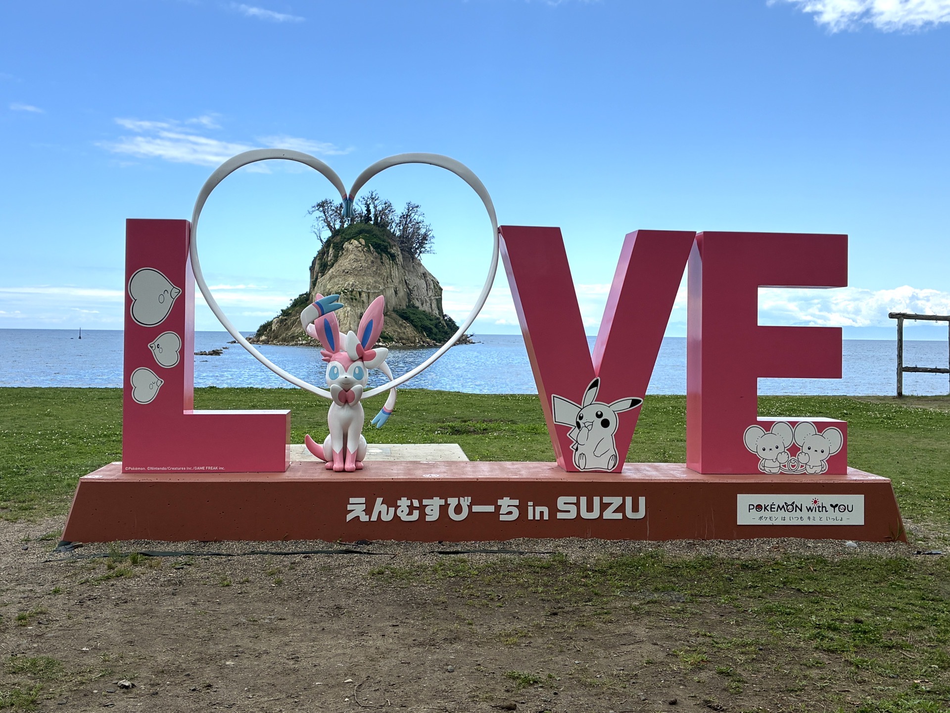ニンフィア with LOVE。こちらも画角を調整すると、ニンフィアがつくるハートマークに見附島が入る。ニンフィアの後ろの台には足跡マークがあり、ハートの中に入って写真が撮れるようにもなっている