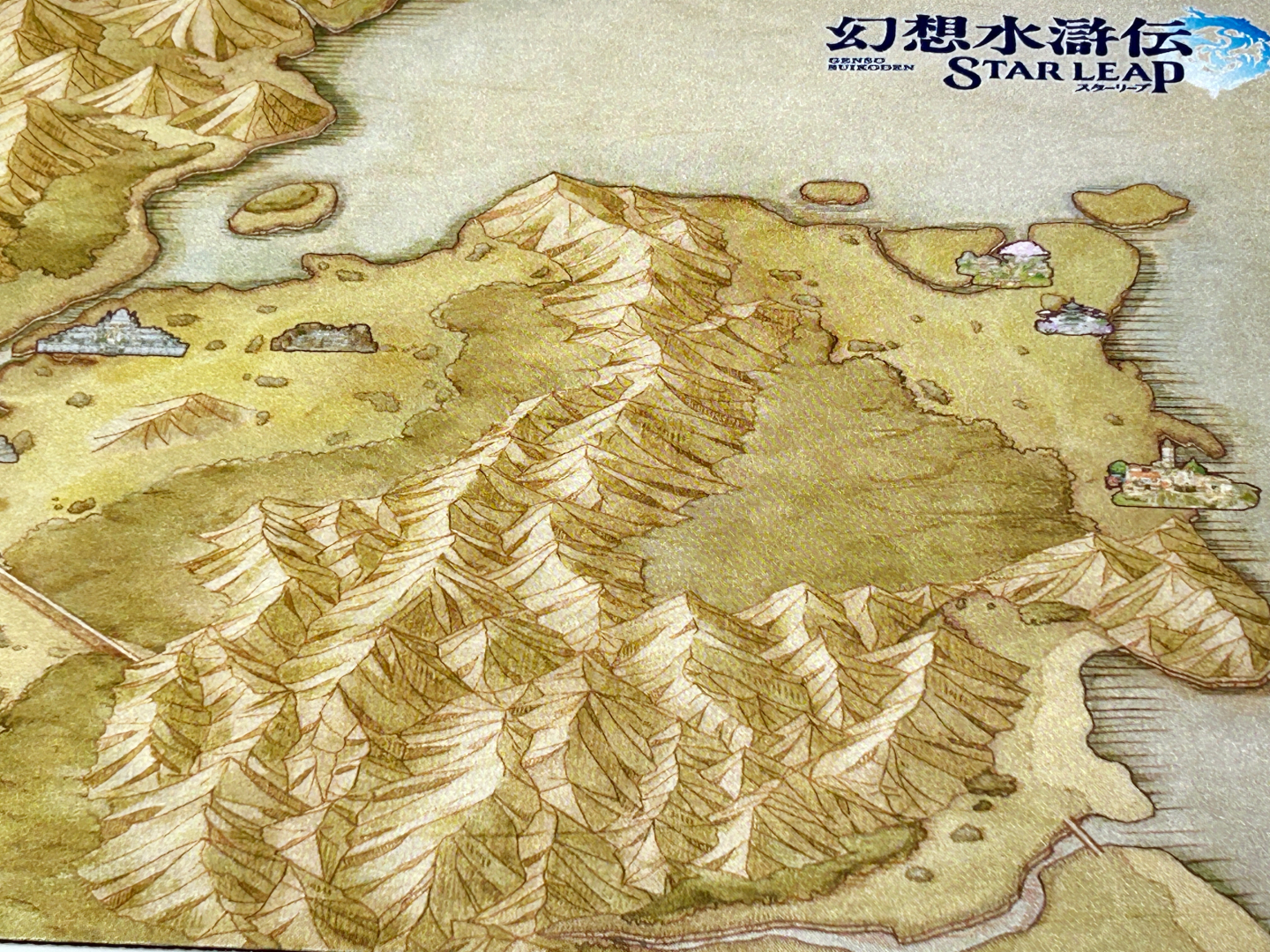 デスクマットにはゲームの舞台となる湖畔の里を中心とした地形図が描かれているので、これを1枚敷くだけで机の上が一気に「幻想水滸伝 STAR LEAP」の世界へと早変わりする。都市や橋なども記載されているので、ゲームをプレイするのにも役立ちそうだ