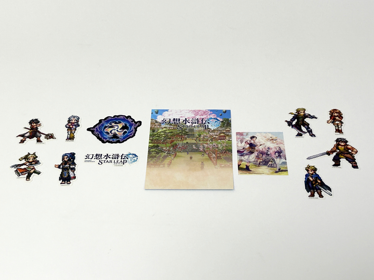 ステッカーセットにはアクリルスタンドと同じキャラクター8人、ロゴと27の真の紋章の一つ・変化の紋章とキービジュアルのステッカー、ドット絵でイラストが描かれたカードが同梱されている。カードの裏面には、公式サイトとX（旧Twitter）へアクセスできるQRコードが印刷されていた