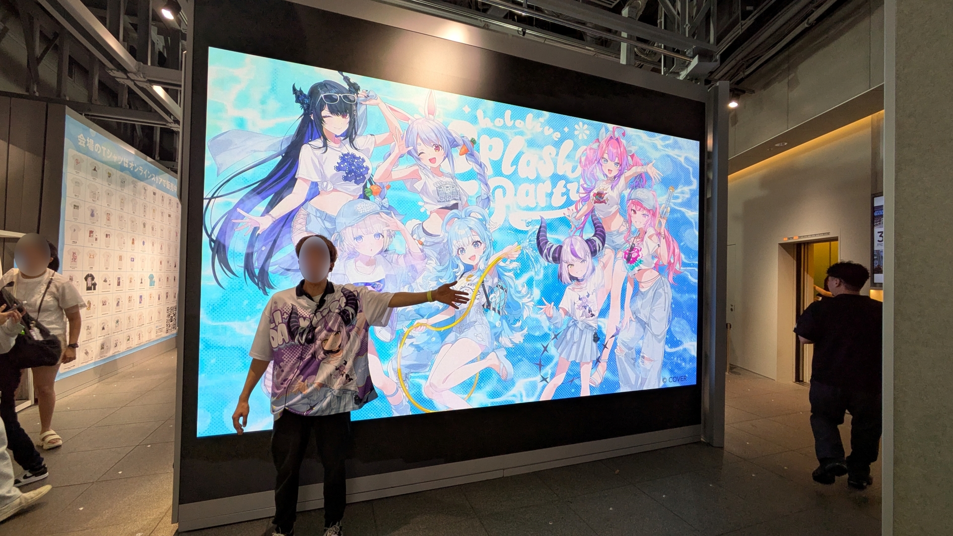 会場入口では大型モニターでPVが上映中。スタッフの皆さんもホロTを着用している